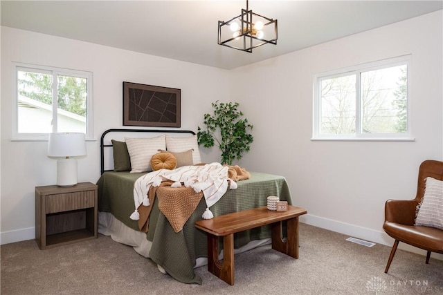 bedroom with an inviting chandelier, light carpet, and baseboards
