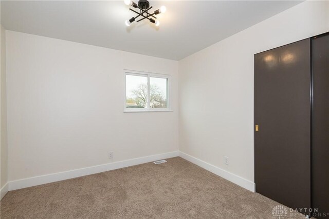 unfurnished bedroom with baseboards, visible vents, and carpet