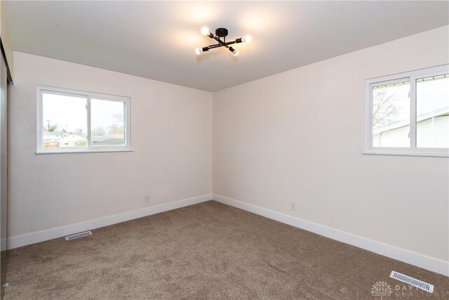 carpeted spare room with baseboards and visible vents