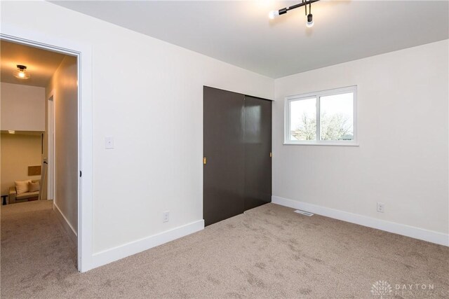 unfurnished bedroom featuring a closet, carpet, baseboards, and visible vents