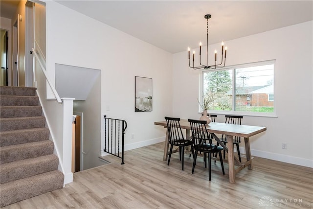 dining room with baseboards, stairway, a notable chandelier, and light wood finished floors