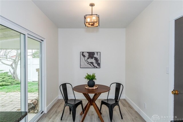 dining area featuring baseboards, light wood-style floors, and a chandelier