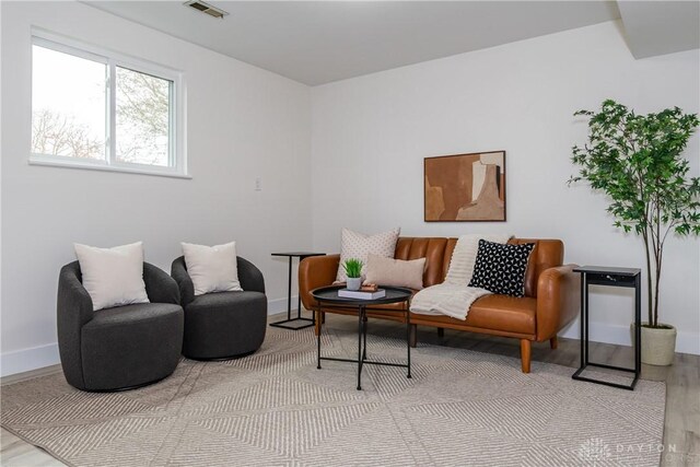 living area with wood finished floors, baseboards, and visible vents
