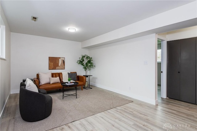 living area featuring baseboards, visible vents, and wood finished floors