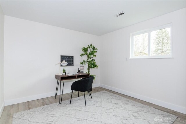 office space with baseboards, visible vents, and wood finished floors