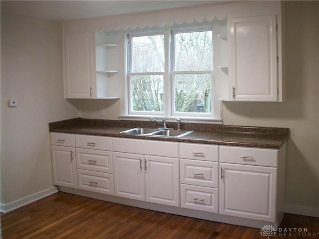 kitchen with a sink, open shelves, dark wood-style floors, dark countertops, and white cabinets