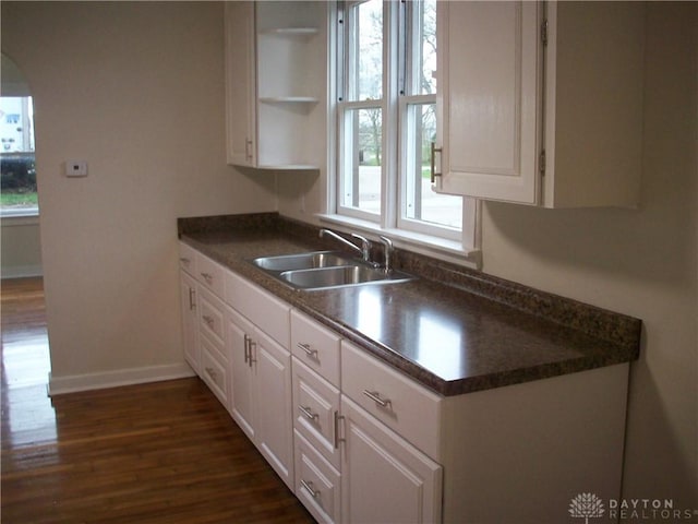 kitchen featuring white cabinetry, a sink, dark countertops, and open shelves