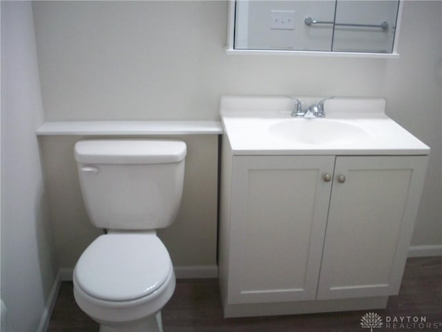 bathroom featuring toilet, vanity, baseboards, and wood finished floors