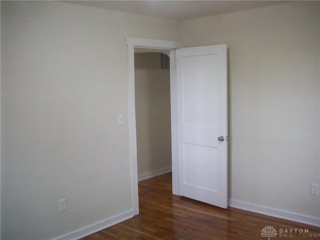 unfurnished room featuring baseboards, visible vents, and wood finished floors