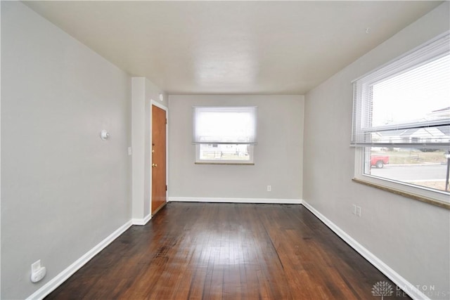 spare room featuring a wealth of natural light, hardwood / wood-style flooring, and baseboards