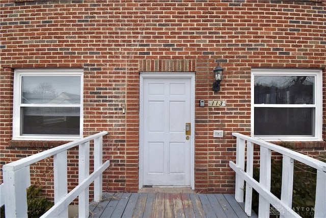 doorway to property featuring a deck and brick siding