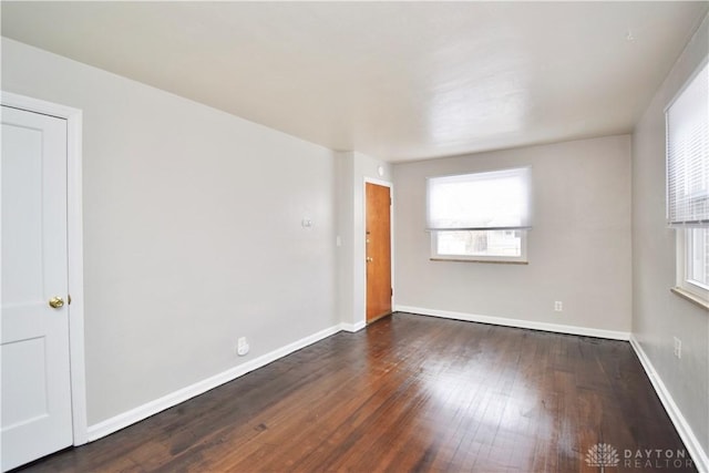 spare room with baseboards and wood finished floors