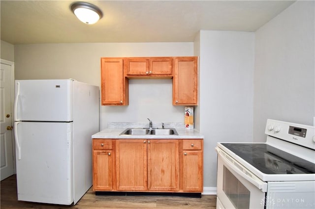 kitchen featuring light countertops, white appliances, a sink, light wood-style floors, and brown cabinets