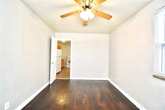 spare room with baseboards, dark wood-style flooring, and a ceiling fan
