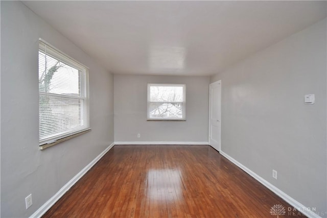 unfurnished room featuring baseboards, wood-type flooring, and a healthy amount of sunlight