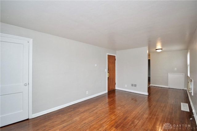 empty room with baseboards, visible vents, and wood finished floors