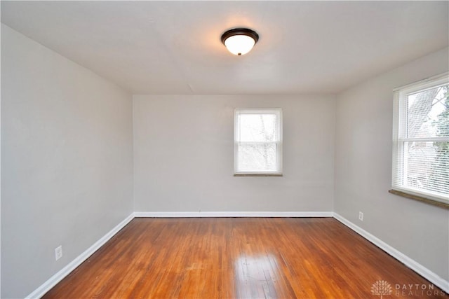 spare room with baseboards and wood finished floors