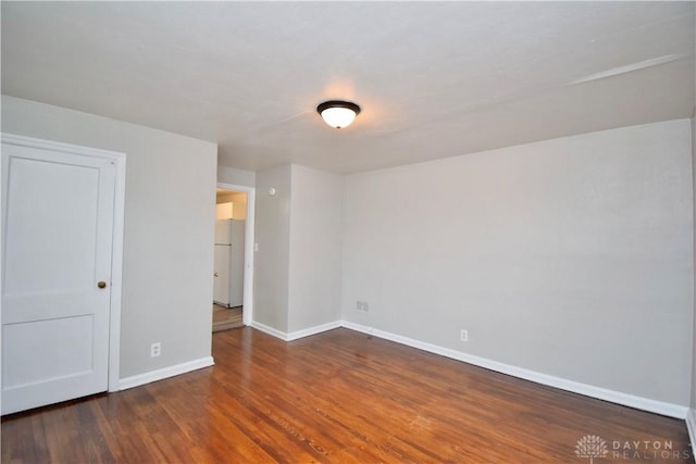 spare room featuring baseboards and wood finished floors