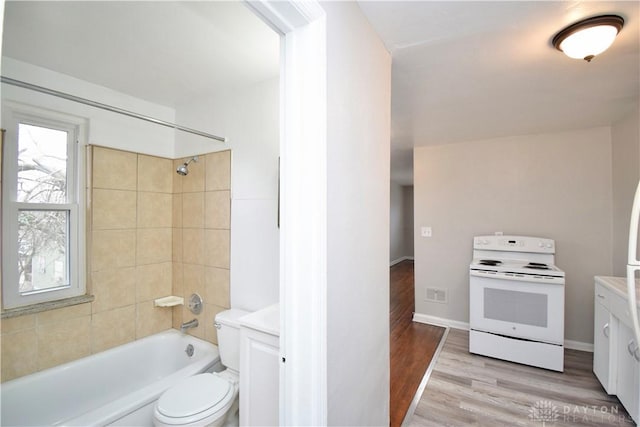 bathroom with toilet, wood finished floors, baseboards, visible vents, and shower / bath combination