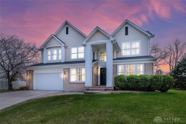 traditional-style house featuring fence, an attached garage, brick siding, concrete driveway, and a lawn