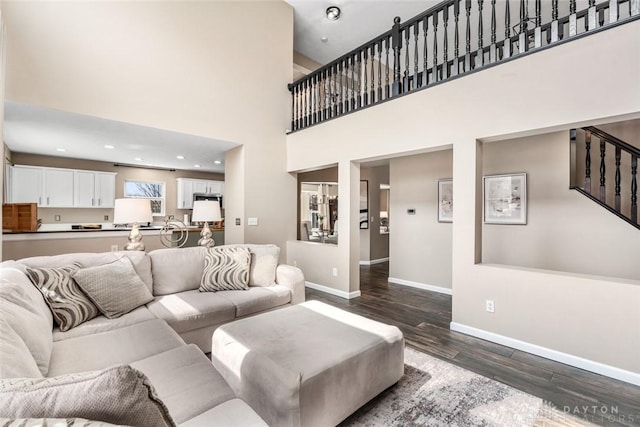 living area featuring recessed lighting, baseboards, a high ceiling, and dark wood-style flooring