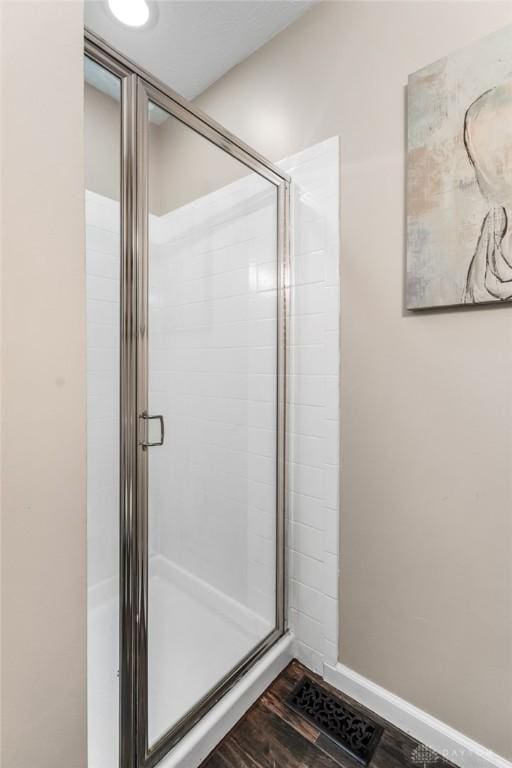full bath with visible vents, baseboards, wood finished floors, and a shower stall