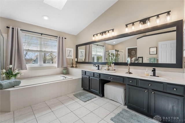 bathroom featuring a garden tub, a sink, vaulted ceiling with skylight, and a wealth of natural light