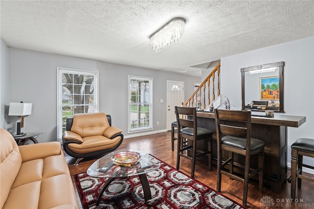 living area with stairs, a textured ceiling, and wood finished floors