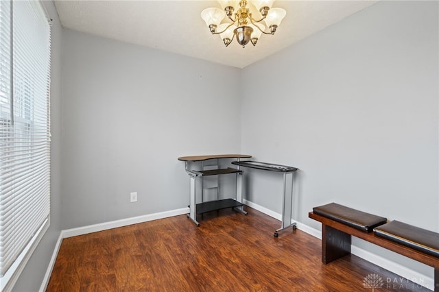 interior space with a chandelier, wood finished floors, and baseboards