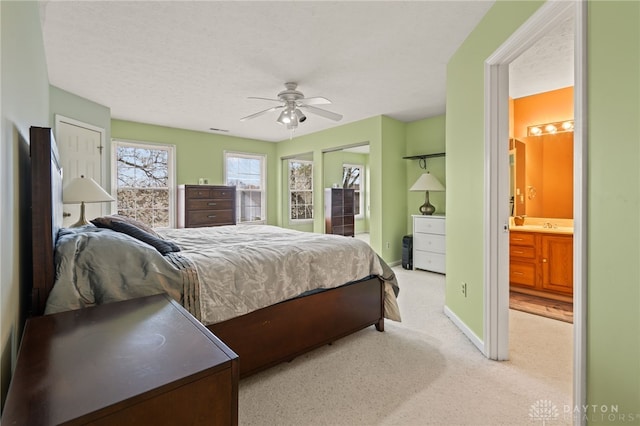 carpeted bedroom featuring ensuite bathroom, baseboards, and a ceiling fan