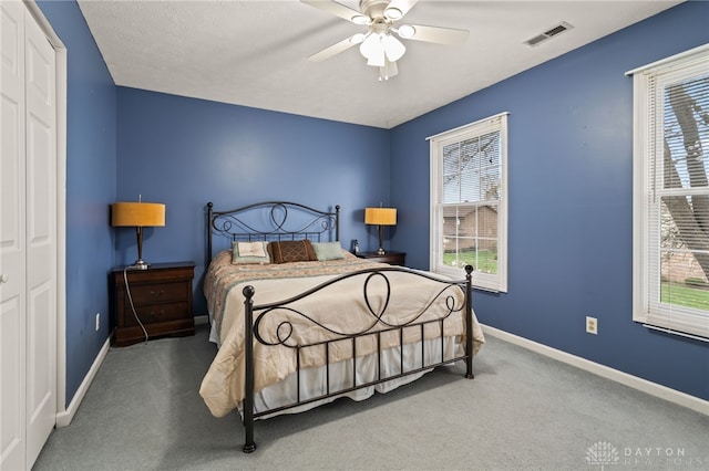 carpeted bedroom with visible vents, baseboards, and a ceiling fan
