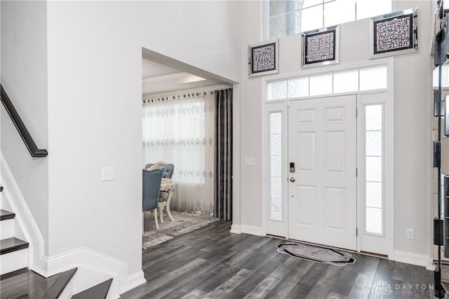 entryway with a towering ceiling, a healthy amount of sunlight, stairway, and dark wood finished floors