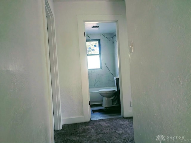 corridor with carpet floors and a textured wall