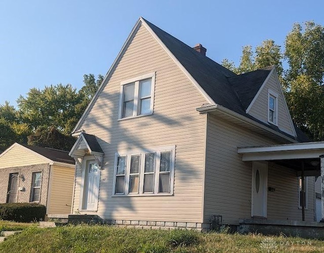 view of front facade with entry steps and a chimney