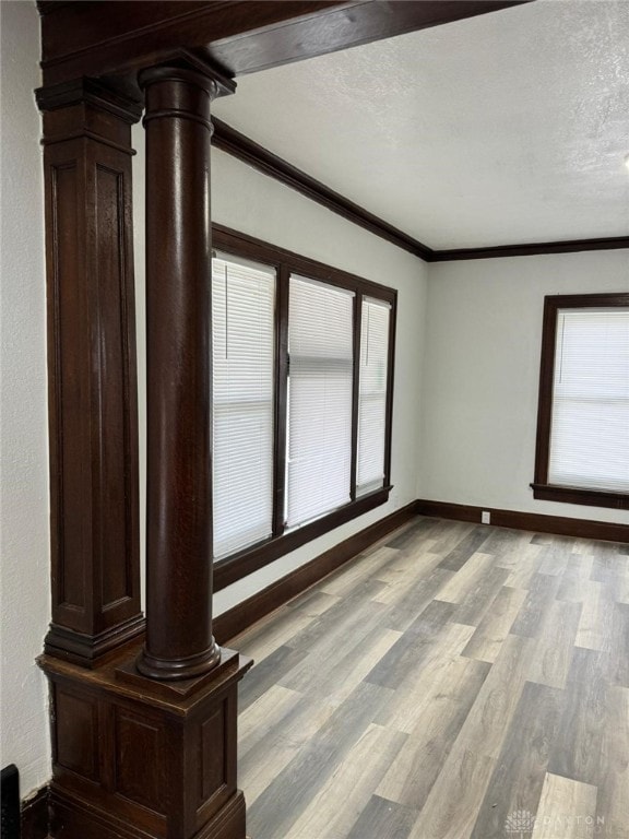 2312 Parkland Ave, Dayton, OH 45405 - unfurnished room featuring a textured ceiling, crown molding, light wood-style flooring, and ornate columns