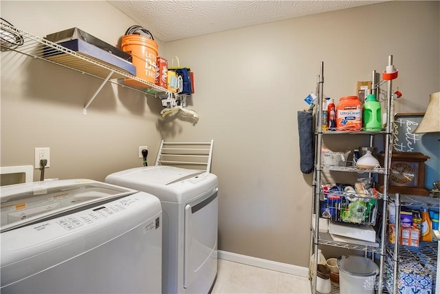 clothes washing area featuring baseboards, tile patterned flooring, laundry area, and washing machine and dryer