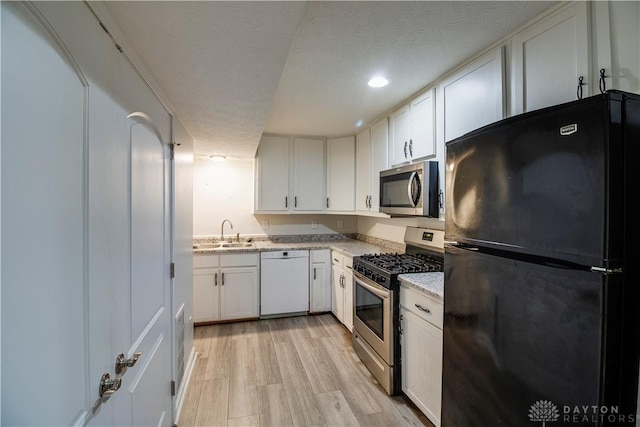 kitchen featuring a sink, white cabinets, light wood-style flooring, and stainless steel appliances