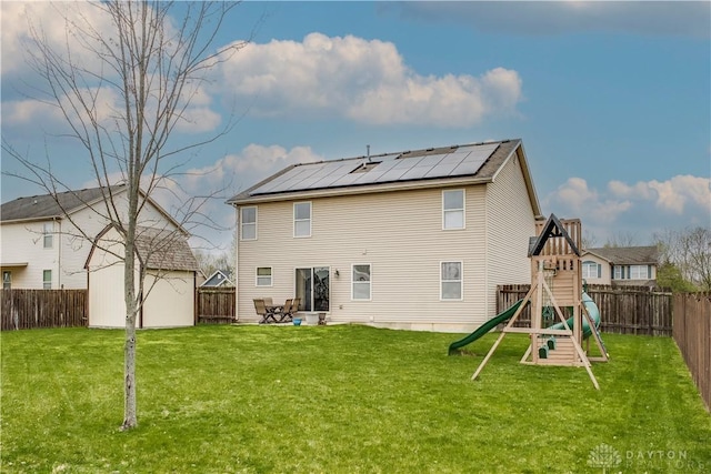 back of house featuring a lawn, a fenced backyard, and a playground