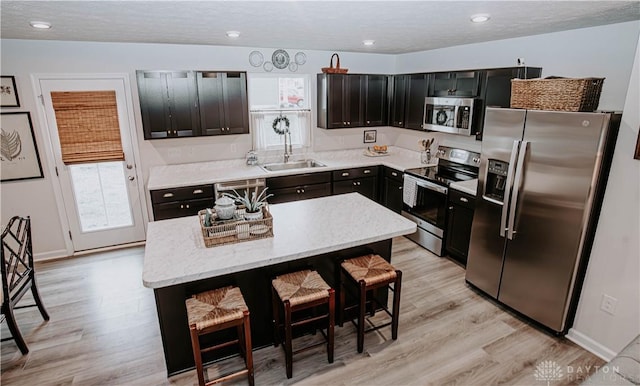 4249 Willow Hills Dr, Dayton, OH 45404 - kitchen with stainless steel appliances, a sink, light wood-style floors, a kitchen island, and a breakfast bar