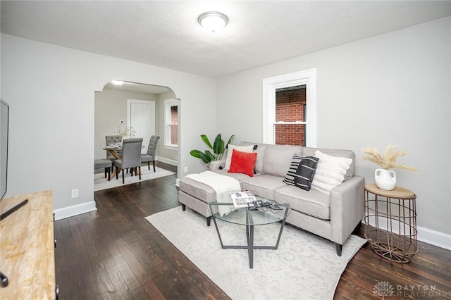 living area featuring baseboards, arched walkways, and hardwood / wood-style floors
