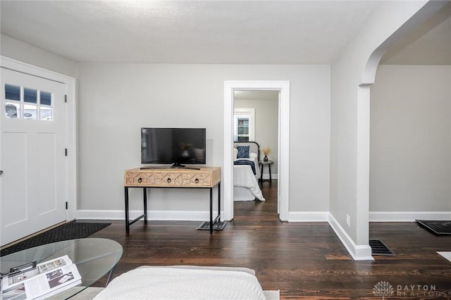 foyer with baseboards, arched walkways, and wood finished floors