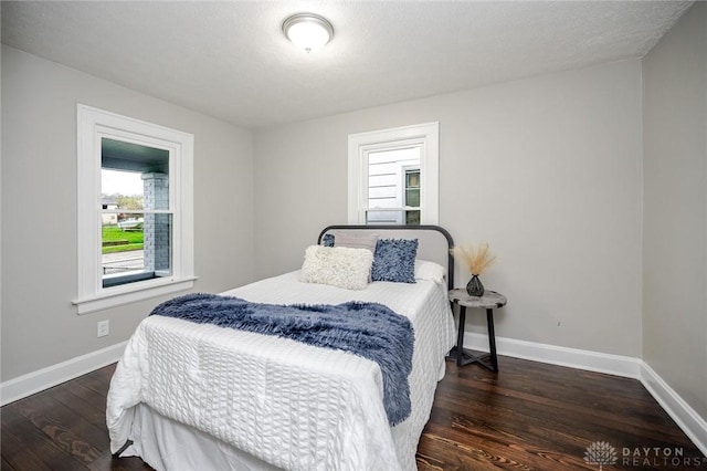 bedroom featuring dark wood-type flooring, a textured ceiling, and baseboards