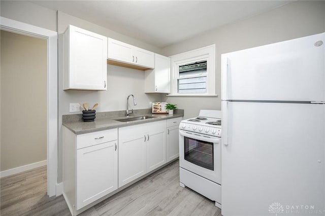 kitchen with white appliances, light wood-type flooring, white cabinets, a sink, and baseboards