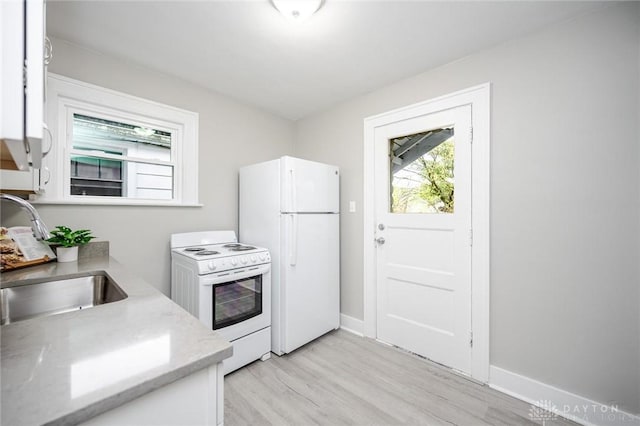 kitchen featuring baseboards, white appliances, light stone countertops, light wood finished floors, and a sink