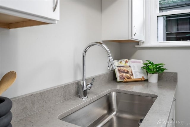 room details featuring white cabinets, light countertops, and a sink