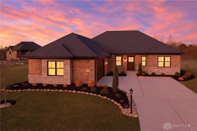 view of front facade with a shingled roof, stone siding, a garage, a front lawn, and driveway