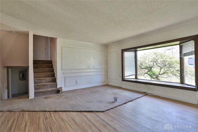 unfurnished living room with stairway, wood finished floors, and a textured ceiling