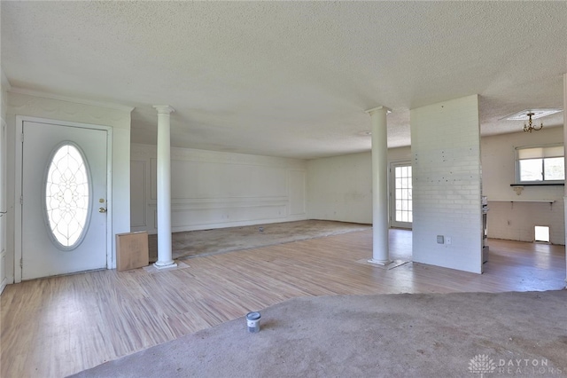 entryway with wood finished floors, a textured ceiling, and decorative columns