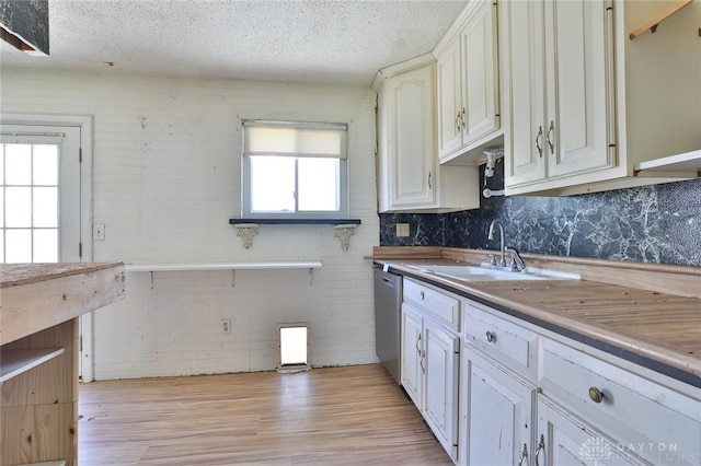 kitchen featuring stainless steel dishwasher, open shelves, a sink, a textured ceiling, and light wood-style floors