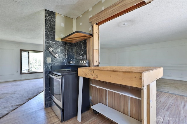 kitchen with stainless steel range with electric cooktop, a textured ceiling, and light wood-type flooring